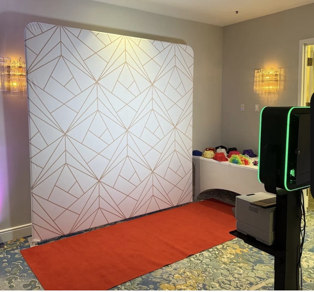 The White & Gold backdrop set up at an event beside the photo booth